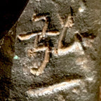 Primer plano de la marca de Hirokazu Mizushima en la escultura de bronce de dos ciervos. La luz resalta los caracteres incisos sobre el metal oscuro y texturizado, con restos de pátina verde alrededor de los trazos.
