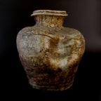 Antique Shigaraki stoneware jar with a flared rim, incised shoulder decoration, pale green ash glaze, and a deeply slumped section of its rounded body.