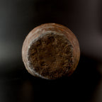 Underside of an antique Shigaraki stoneware jar, showing its roughly circular, unglazed base with coarse dark brown clay and a surrounding ring of reddish stoneware.