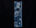 Long, narrow antique Japanese boro cotton panel displayed vertically against a black background. Overlapping patches of dark and faded indigo cotton feature extensive hand stitching, frayed edges, and worn-through areas. A large pale blue patch appears near the top, with smaller patterned cotton patches near the bottom.